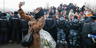 Eine Frau mit Blumen macht ein Selfie, während Menschen, umgeben von der Polizei, zum Borisowskoje-Friedhof gehen, um an der Trauerfeier des russischen Oppositionsführers Alexej Nawalny in Moskau teilzunehmen