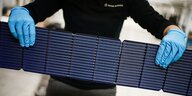 Arbeiter hält Solarmodul in den Händen