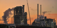 Eine große Industrieanlage mit vielen dampfenden Schornsteinen erzeugt Treibhausgase.