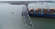 Ein Foto aus der Vogelperspektive zeigt das Containerschiff und die eingestürzte Brücke auf dem Patapsco River in Baltimore bei Tage.