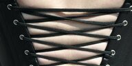 Rückenansicht einer Frau mit einem schwarzen, eng geschnürten Korsett