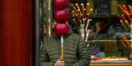Ein Verkäufer hält vor seinem Geschäft in Peking einen riesigen nachgemachten, mit Zucker überzogenen chinesischen Haw (gezuckerte Früchte) vor sein Gesicht