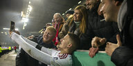 Düsseldorfs Stürmer Christos Tzolis macht am Spielfendrand ein Selfie mit Fans