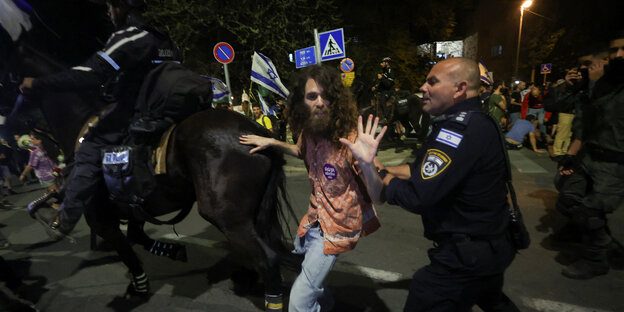 Ein Protestierender zwischen einem Polizeipferd und einem Polizisten