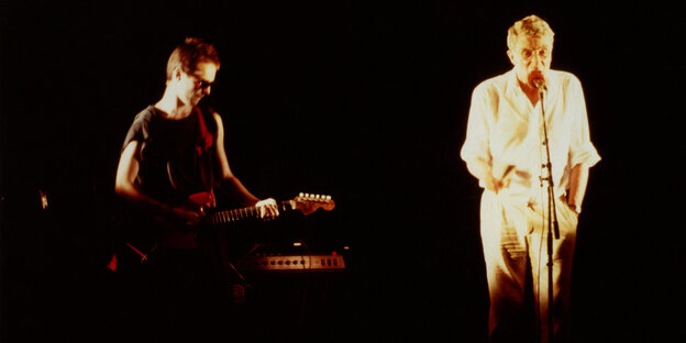 Twee mensen spelen gitaar en zingen op een podium