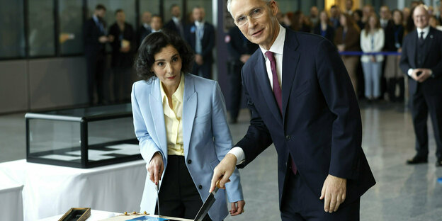 NAVO-secretaris-generaal Jens Stoltenberg en de Belgische minister-generaal Hadja Lahbib schneiden Schokoladentorte an.