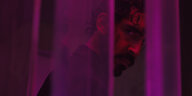 Hauptdarsteller Dev Patel in dunklem Licht hinter einem transparentem Vorhang