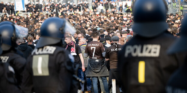 Fans des FC St. Pauli gehen ins Volksparkstadion, im Vordergrund sind Polizeibeamte zu sehen.