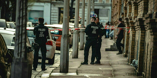 Polizei steht vor einem Wohnhaus in Halle, ein Bereich ist mit Flatterband abgesperrt.