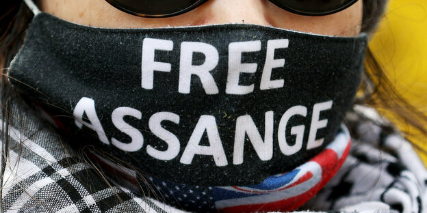 Een persoon draagt ​​een masker met een kopie van Free Assange