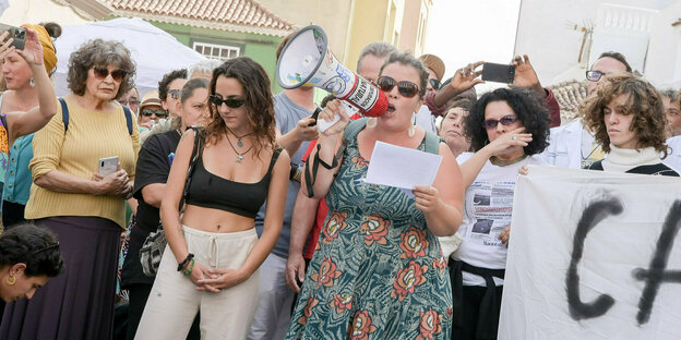Einwohner von Tnerife stehen mit einem Mefaphon und einem Plakat auf einem Platz und demonstrieren gegen die Auswüchse des Tourismus auf der Insel