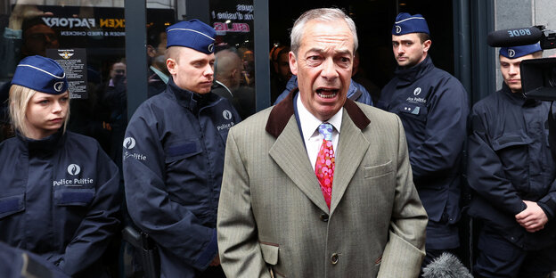 Politiker Nigel Farage vor Polizisten.