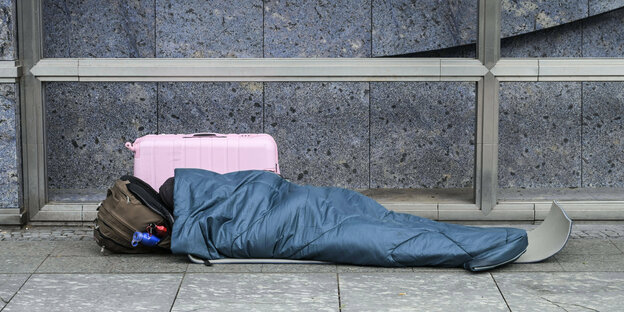 Ein Obdachloser schläft auf der Straße.