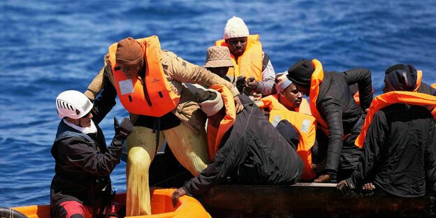 Motorsegler helfen Migranten beim Umstieg von einem überfüllten, kentergefährdeten Stahlboot auf ihr Beiboot.