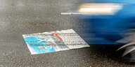 Ein AfD-Wahlplakat auf der Straße, über das ein Auto gefahren ist