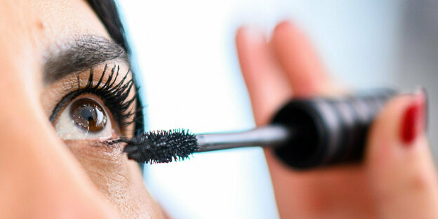 Eine Frau schminkt ihre Augen mit Mascara