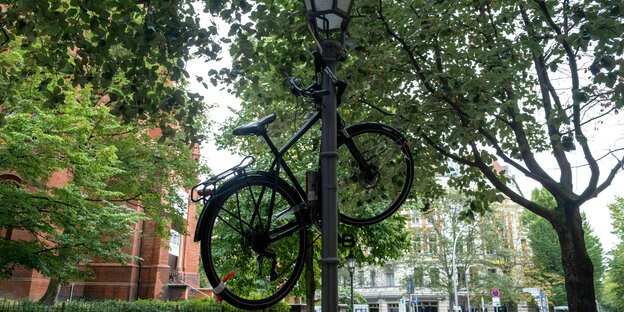Ein Fahrrad hängt an einem Laternenpfahl in der Stadt