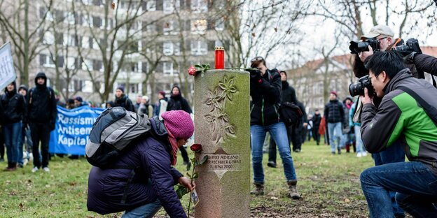 Ein Demonstrant legt 2018 in Dessau Blumen am Gedenkstein für Alberto Adriano nieder
