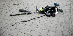 Eine Kamera mit Kabeln und Mikro liegt auf einer gepflasterten Straße