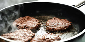 Fleisch Ersatz Burger wird in einer heißen Pfanne mit Öl angebraten