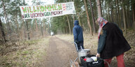 Aktivisten fahren Porridge und Geschirr von der Gemeinschaftsküche zu einem Camp der Initiative «tesla stoppen» in einem Kiefernwald nahe der tesla-Gigafactory Berlin-Brandenburg. Zwischen Bäumen ist ein großes Banner gespannt: "Willkommen in der Utopien-