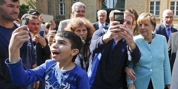Ein junger Geflüchteter macht ein Selfie von sich und Angela Merkel Ein junger Geflüchteter macht ein Selfie von sich und Angela Merkel