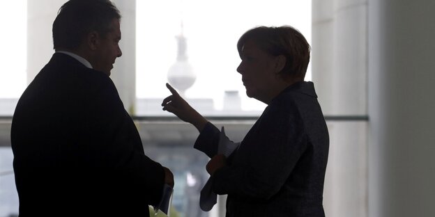 Zwei Menschen im Schatten stehen im Profil vor einem hellen Hintergrund, Zwei Menschen im Schatten stehen im Profil vor einem hellen Hintergrund,