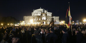 Menschenmassen stehen im Dunkeln vor der Semperoper in Dresden