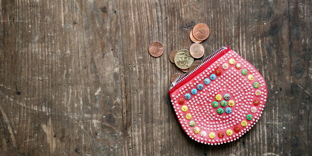 Eine bunte Geldbörse und Münzen liegen auf einem Holztisch Eine bunte Geldbörse und Münzen liegen auf einem Holztisch