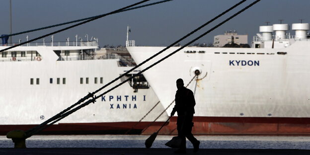 Straßenfeger vor einem Schiff im Hafen