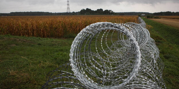 Ein Stacheldrahtzaun durchschneidet eine Landschaft Ein Stacheldrahtzaun durchschneidet eine Landschaft