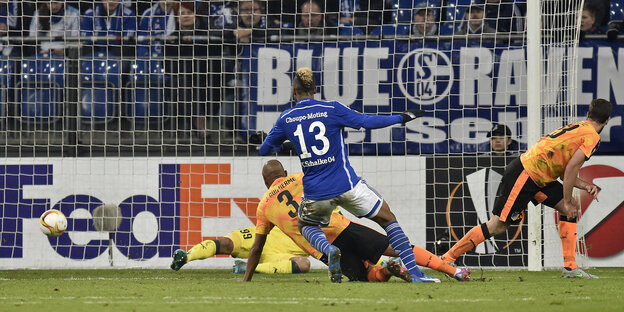 Fußballfeld, Spieler in blauem Trikot mit Nummer 13 schießt ein Tor Fußballfeld, Spieler in blauem Trikot mit Nummer 13 schießt ein Tor