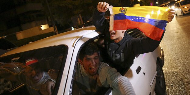 Männer im Auto schwenken die venezolanische Flagge. Männer im Auto schwenken die venezolanische Flagge.