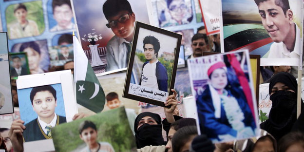Angehörige der Opfer von Peshawar halten Bilder der Getöteten hoch.