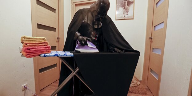 Ein Mann im Darth-Vader-Kostüm bügelt Ein Mann im Darth-Vader-Kostüm bügelt