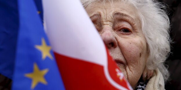 Eine ältere Frau hinter einer polnischen Flagge und einer EU-Flagge Eine ältere Frau hinter einer polnischen Flagge und einer EU-Flagge