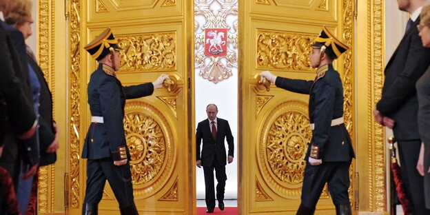 Wladimir Putin schreitet durch eine riesige goldene Flügeltür, die von zwei Uniformierten geöffnet wird Wladimir Putin schreitet durch eine riesige goldene Flügeltür, die von zwei Uniformierten geöffnet wird