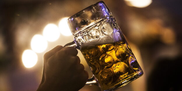 Hand hält eine Maß Bier in den Nachthimmel Hand hält eine Maß Bier in den Nachthimmel