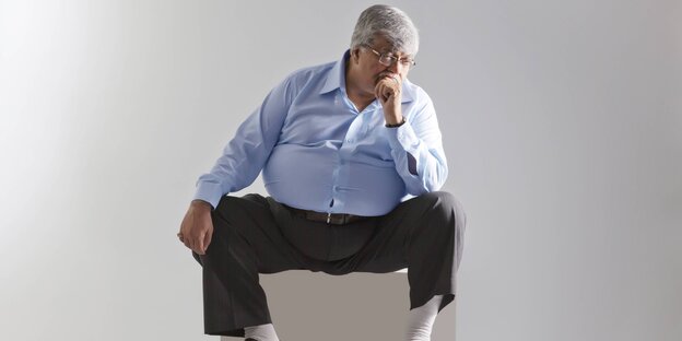 Ein dicker Mann sitzt auf einem Hocker Ein dicker Mann sitzt auf einem Hocker
