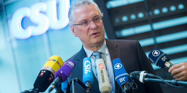 Joachim Herrmann vor einem Logo der CSU, vor ihm zahlreiche Mikrofone Joachim Herrmann vor einem Logo der CSU, vor ihm zahlreiche Mikrofone