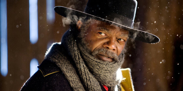 Ein Mann mit Schal und Hut guckt in die Kamera, es ist Samuel L. Jackson Ein Mann mit Schal und Hut guckt in die Kamera, es ist Samuel L. Jackson