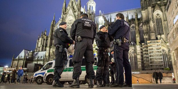 Eine Gruppe Polizist_innen steht am Abend am Kölner Hauptbahnhof Eine Gruppe Polizist_innen steht am Abend am Kölner Hauptbahnhof