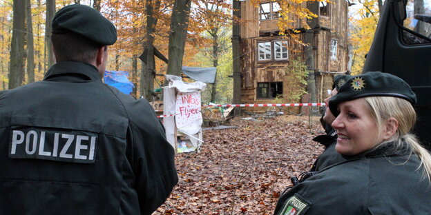 Zwei Polizisten stehen im Wald vor einem Camp von Anti-Braunkohle-Aktivisten. Zwei Polizisten stehen im Wald vor einem Camp von Anti-Braunkohle-Aktivisten.