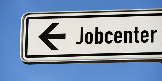 Auf einem Wegweiser steht „Jobcenter“ und ein Pfeil, der nach links zeigt. Auf einem Wegweiser steht „Jobcenter“ und ein Pfeil, der nach links zeigt.