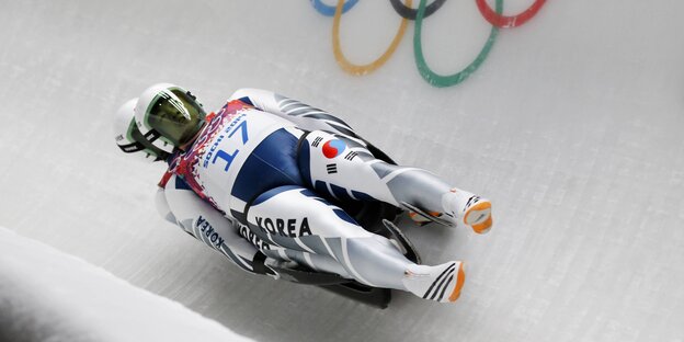 Zwei Doppelsitzrodler aus Korea fahren durch einen Eiskanal, in dem die Olympischen Ringe zu sehen sind. Zwei Doppelsitzrodler aus Korea fahren durch einen Eiskanal, in dem die Olympischen Ringe zu sehen sind.