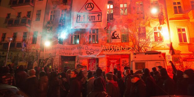 Demonstranten vor einer rot erleuchteten Hausfront Demonstranten vor einer rot erleuchteten Hausfront