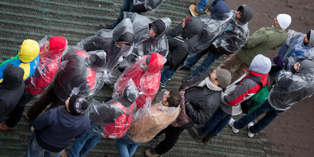 Menschen in Regenkleidung stehen in einer Schlange an. Menschen in Regenkleidung stehen in einer Schlange an.