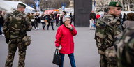 Eine ältere Dame in Rot zwischen zwei Soldaten auf den Champs-Élysées in Paris